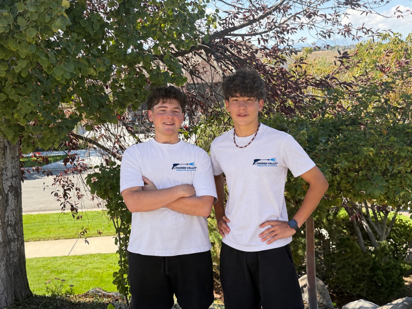 Zander and Cameron, the two owners of Hidden Valley Pressure Washing, standing outside in branded white company shirts